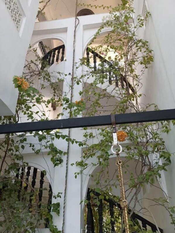 A multi-level courtyard with white walls, arches, and a black balustrade.
