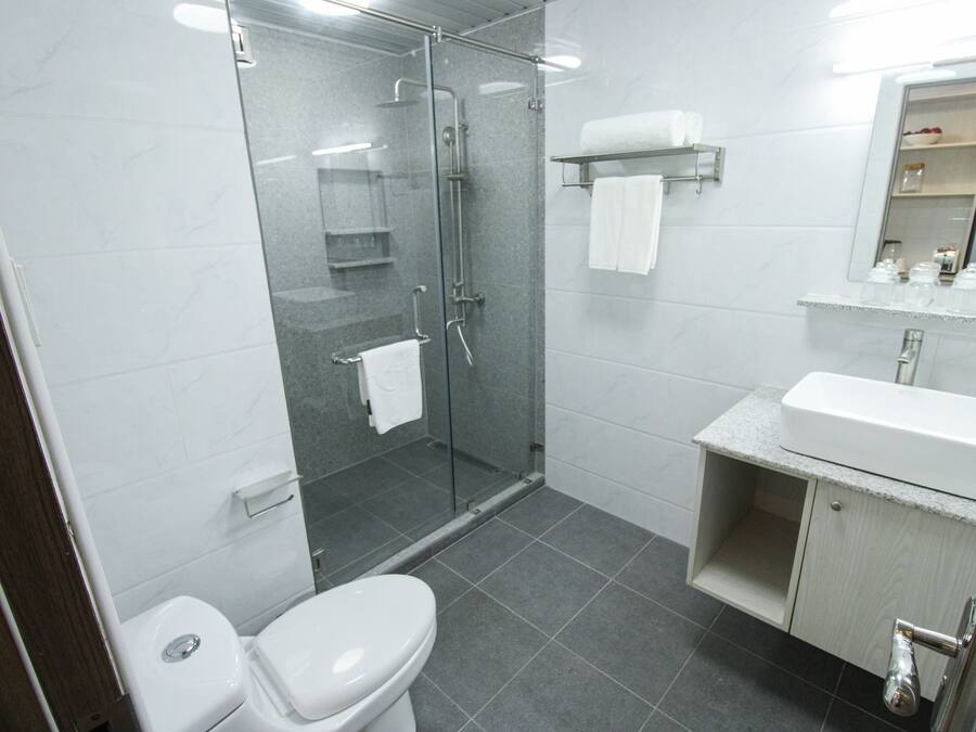 Een moderne badkamer met een douchecabine van glas, een wit toilet en een wastafel met een aanrechtblad.