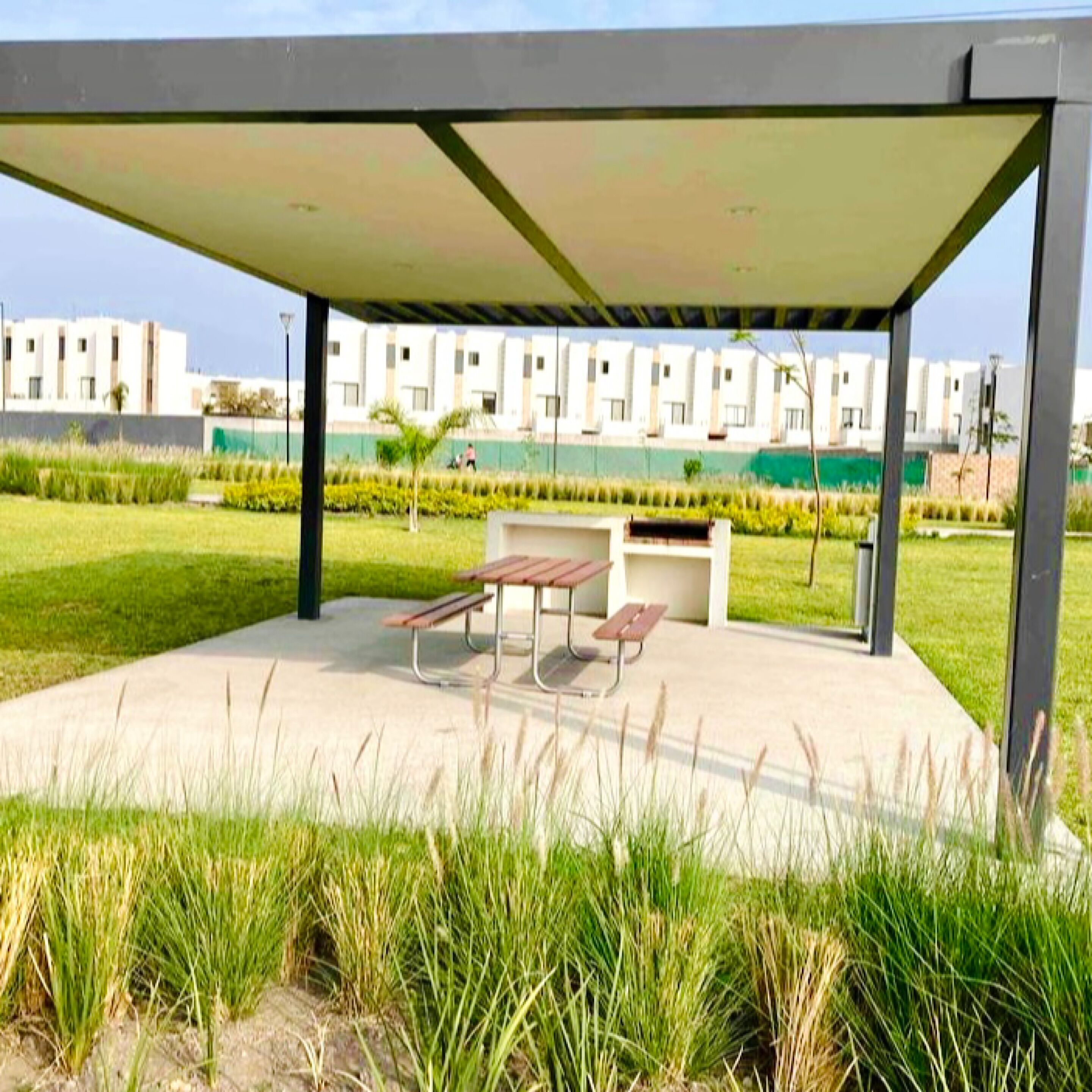 Un espacio de estar al aire libre con techo, bancos y vistas a edificios modernos.