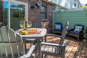 En terrasse med et spisebord, udendørs stole og en ventilator.