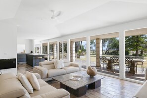 Amplia sala de estar con un sofá grande, una mesa de centro y un comedor con asientos al aire libre.