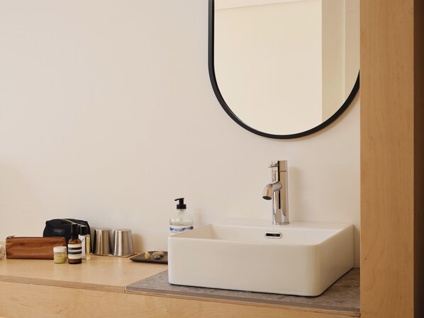 A bathroom with a white sink, a mirror with a black frame, and toiletries on the counter.