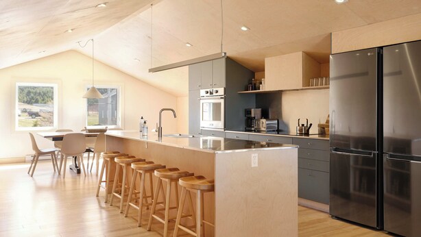Een moderne keuken met een centraal eiland, een bar met barkrukken, een koelkast en een eetgedeelte met uitzicht.