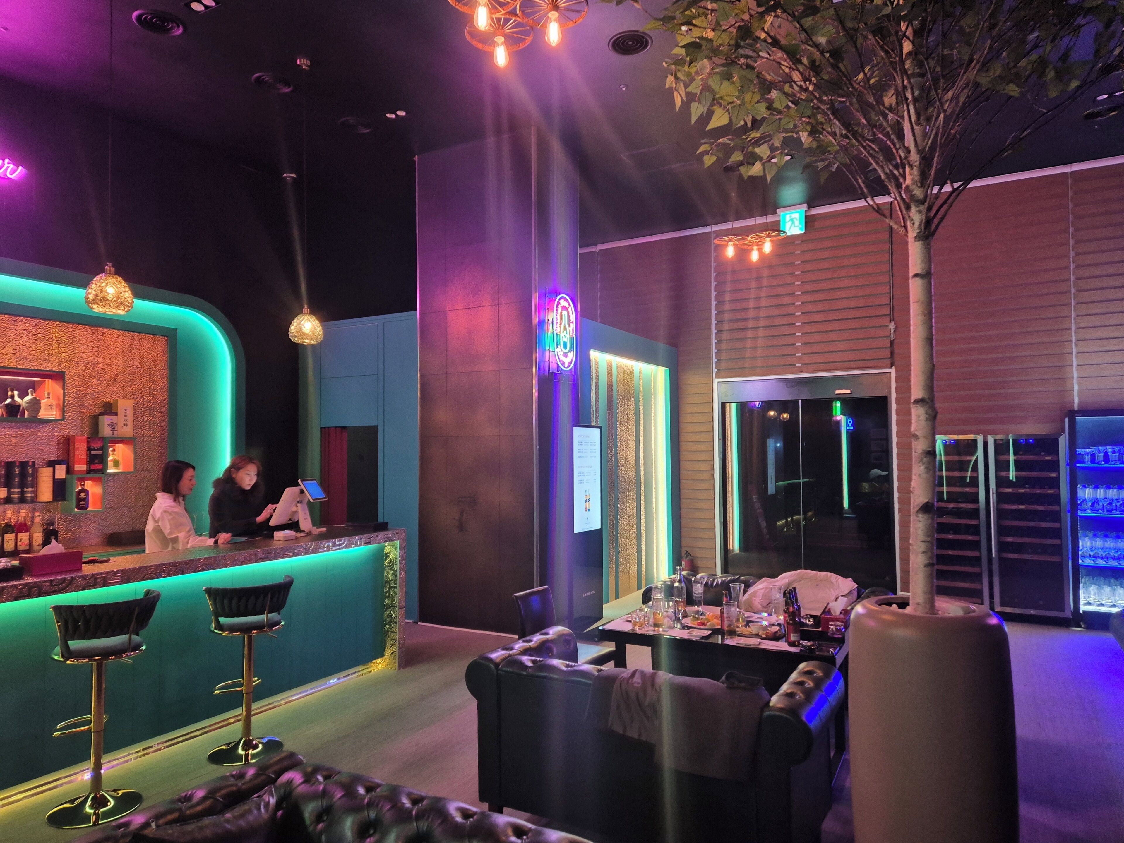 A bar area with a counter, stools, and a seating area with a table and chairs.