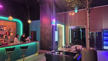 A bar area with a counter, stools, and a seating area with a table and chairs.