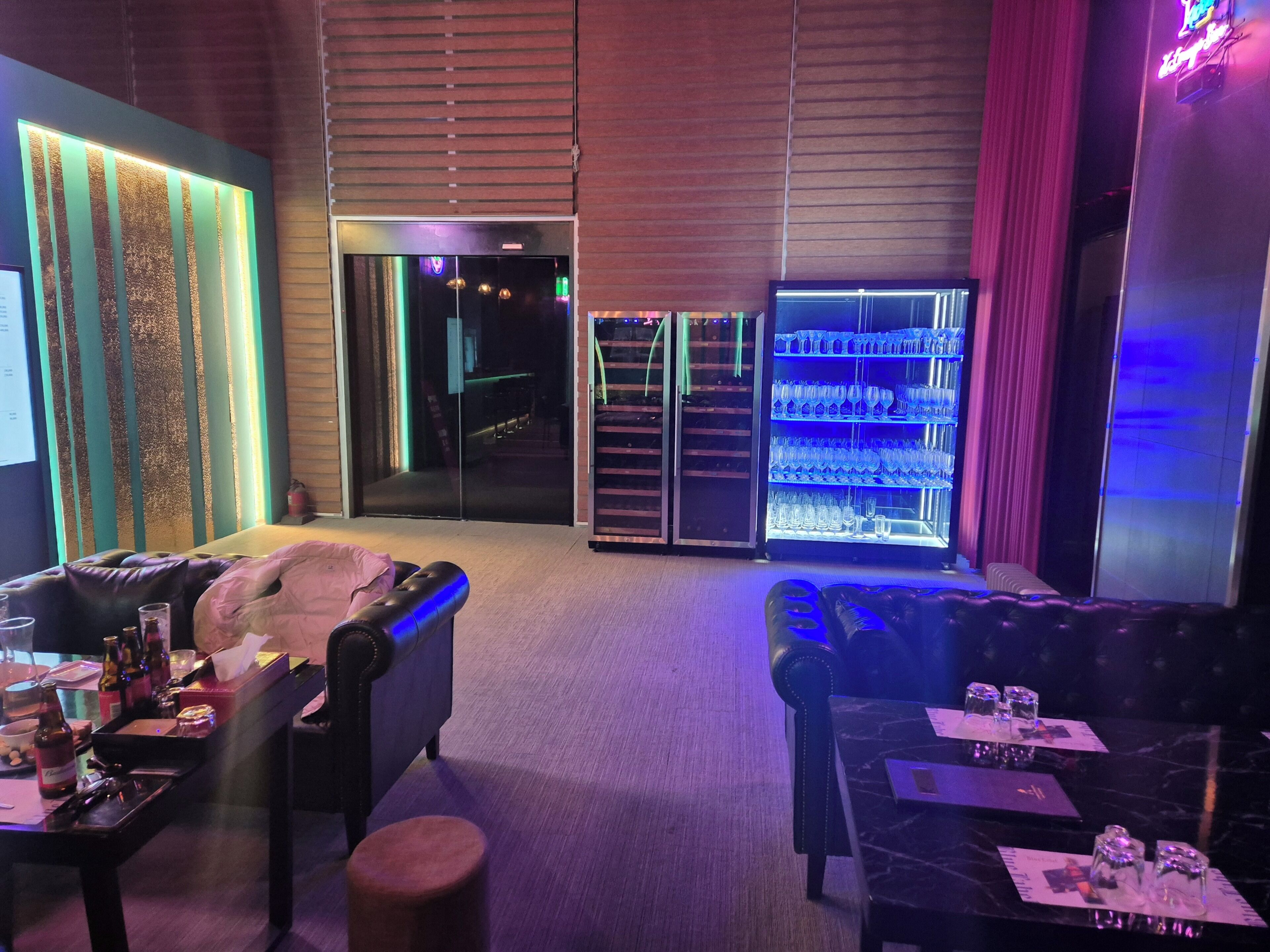 A room with a sofa, a table with bottles, and a bar area with glasses.