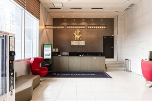 A modern reception area with a wooden reception desk, a 'SAVE THE PLANET' poster, and a 'K-TREE' sign. - Ktree Pyeongtaek hotel (Pyeongtaek)