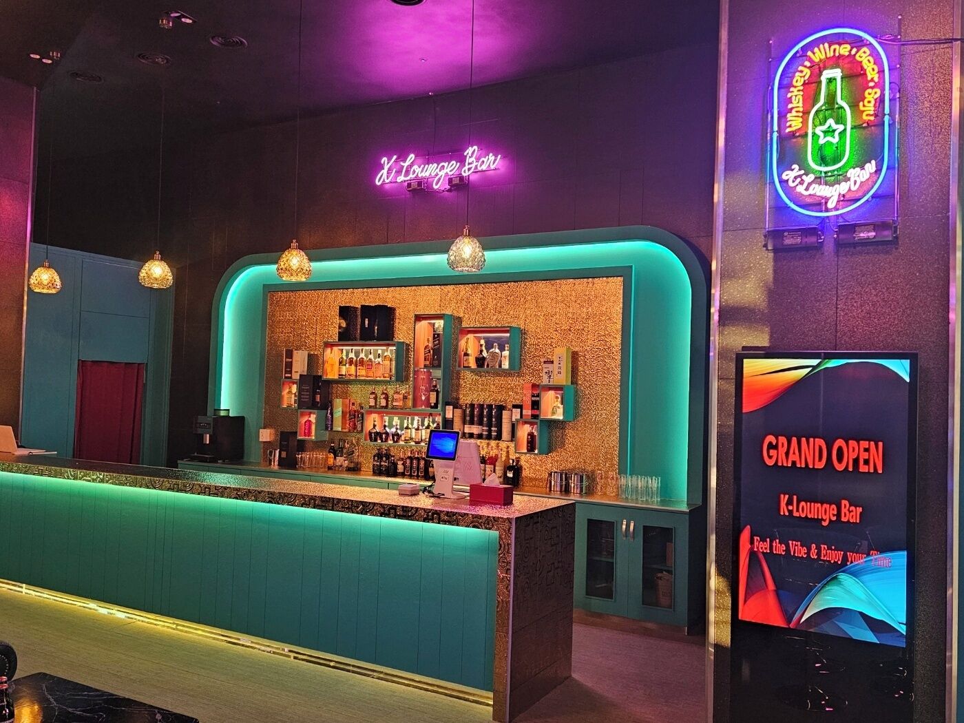 Zona de bar con un letrero de neón, una barra y una exhibición para un evento de inauguración.