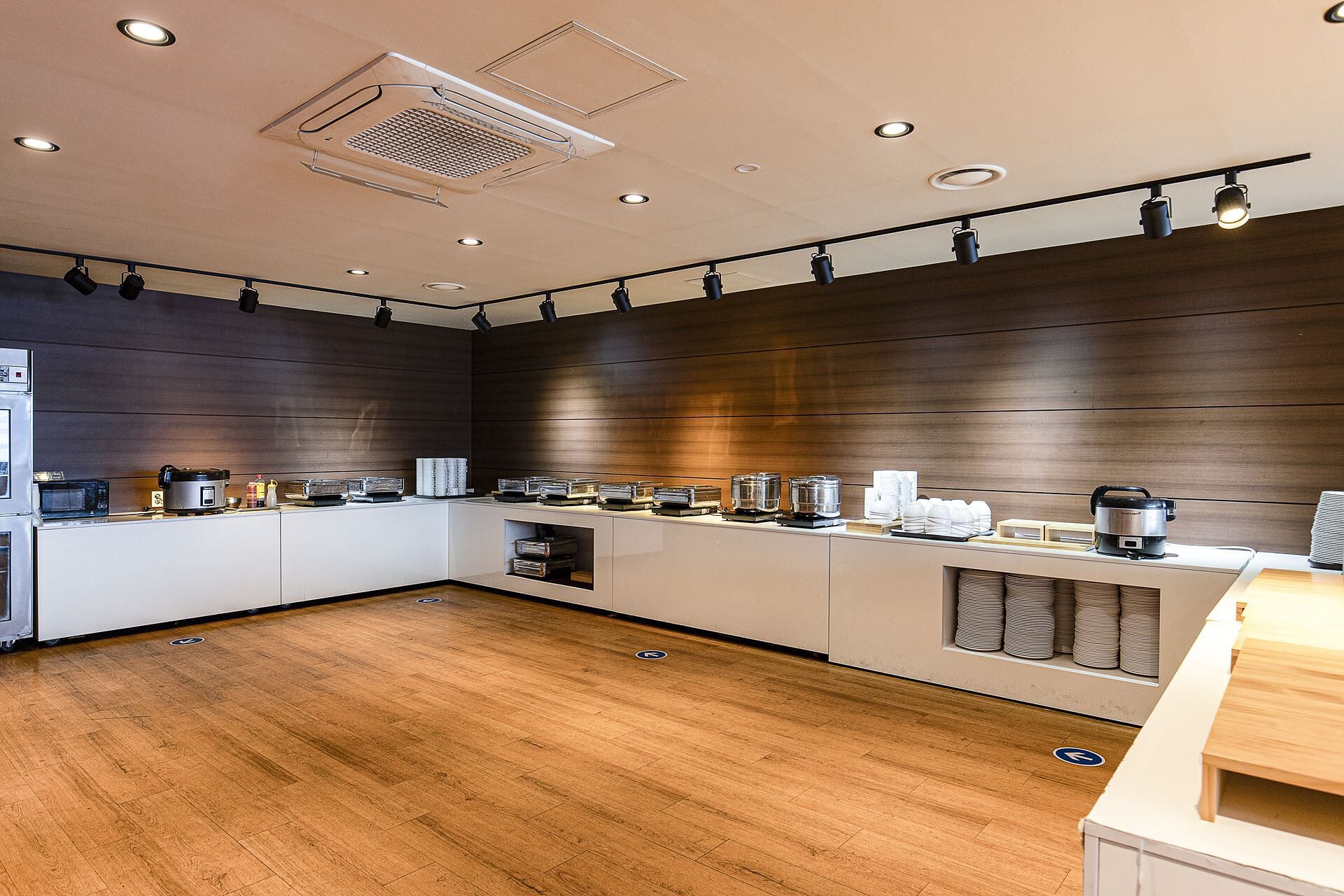 A modern kitchen with a wooden floor, built-in appliances, and a long counter with various kitchenware.