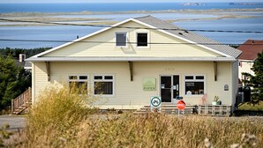 A single-story building with a sign reading 'MAISON PAPIER,' a stop sign, and a view of the ocean.