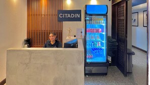 Una zona de recepción con un letrero de 'CITADIN', un refrigerador lleno de bebidas y una máquina de café.