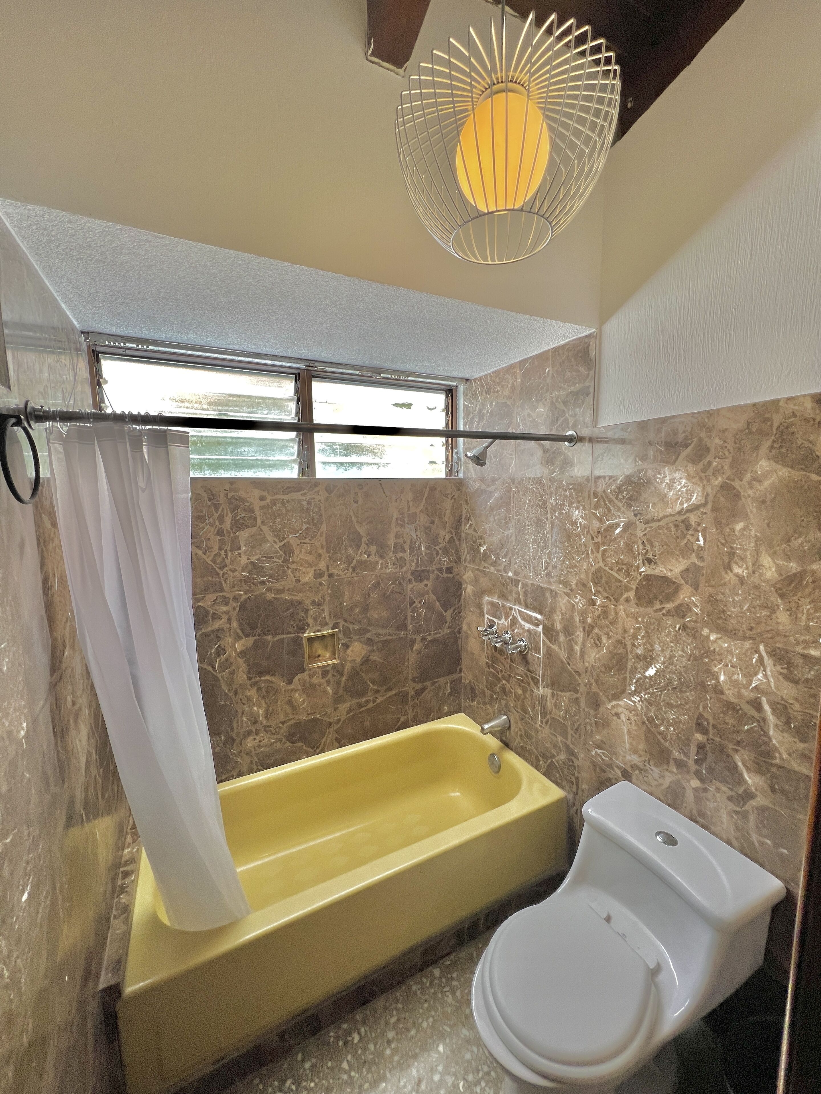 Une salle de bain avec une baignoire, des toilettes et un rideau de douche.