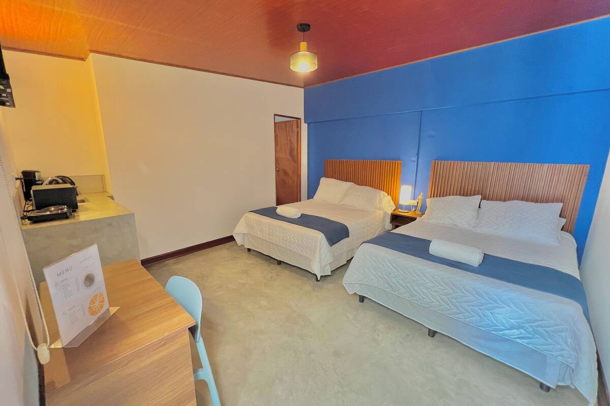 Une chambre d’hôtel avec deux lits, un bureau et une chaise.