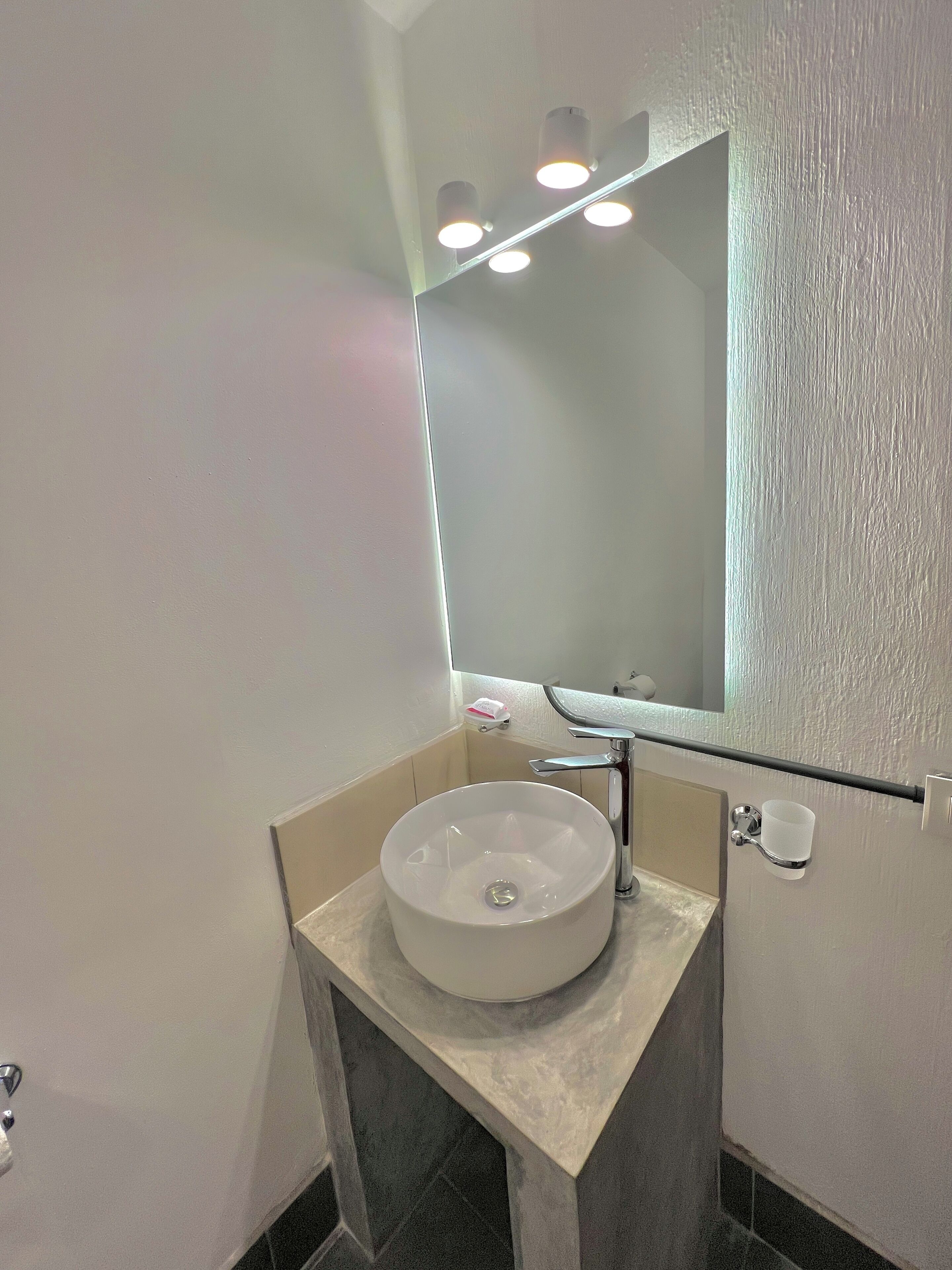 A bathroom with a white sink, a mirror, and a light fixture above the mirror.