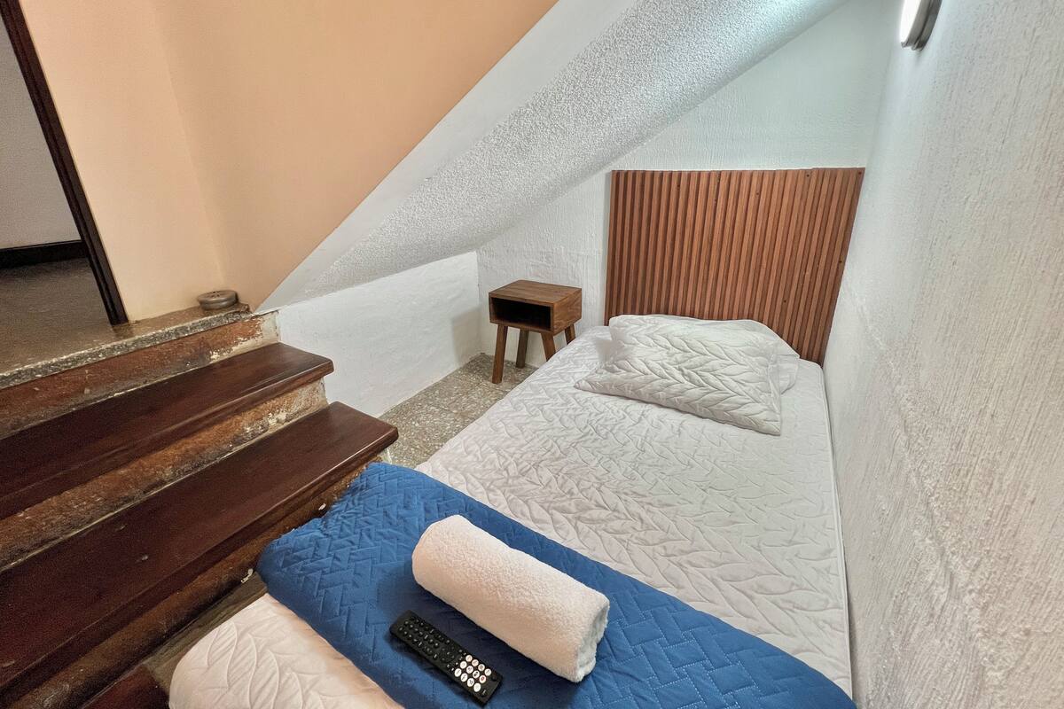Une petite pièce agréable et chaleureuse, avec un lit, une table de chevet en bois et une petite table.