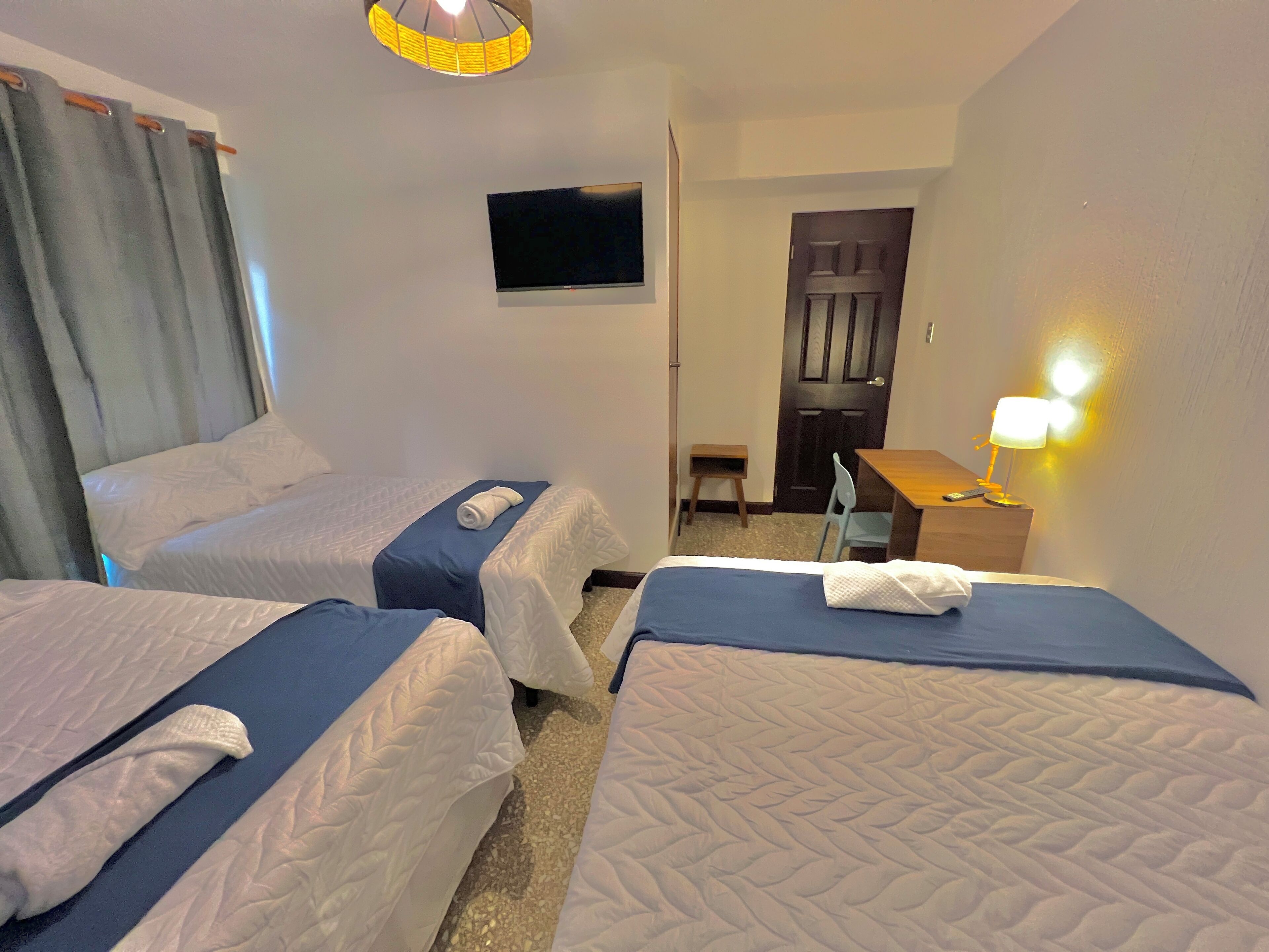 Ein Hotelzimmer mit zwei Betten, einem Schreibtisch, einem Sessel, einem Fernseher und einer Lampe.