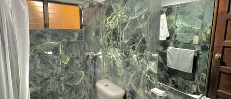 A bathroom with a toilet, sink, and shower area.