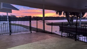 A covered outdoor area with a view of a body of water and a sunset.