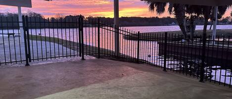 A covered outdoor area with a view of a body of water and a sunset.