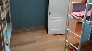A room with a wooden bunk bed, a white door, and a blue wall. - Room-bed 15 in a 6-bed Mixed Dormitory r (Sintra)