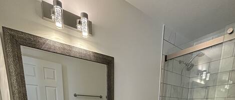 Ein modernes Badezimmer mit großem Spiegel, Waschbecken, Toilette und Duschbereich.