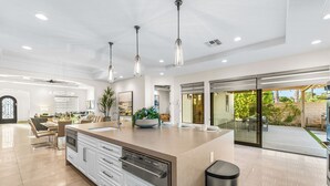 A modern kitchen with a large island, pendant lighting, and a view to the outdoor patio. - Luxury+deals,Cinema,Basketball,Volleyball, Pickleball, Putting Green,Ping Ping (Bermuda Dunes)