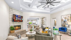 A modern living room with a fireplace, a ceiling fan, and a TV mounted on the wall. - Luxury+deals,Cinema,Basketball,Volleyball, Pickleball, Putting Green,Ping Ping (Bermuda Dunes)