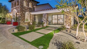 A stone house with a patio, a covered outdoor area, and a well-maintained lawn. - Luxury+deals,Cinema,Basketball,Volleyball, Pickleball, Putting Green,Ping Ping (Bermuda Dunes)