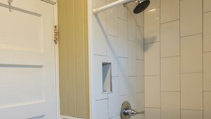 A bathroom with a shower, a towel rack, and a door. - Pool Cottage in Historic Old Town Beaumont (Beaumont)