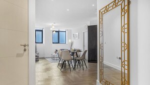 Ein modernes Interieur mit Essbereich, Holzboden und einem großen Spiegel mit geometrischer Riegelrahmung.