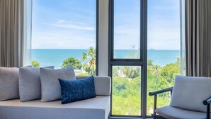 Una sala de estar moderna con un ventanal que ofrece vistas al océano y al follaje.