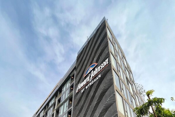 Un hôtel moderne, reconnaissable à son enseigne bien visible indiquant « Howard Johnson by Wyndham ».