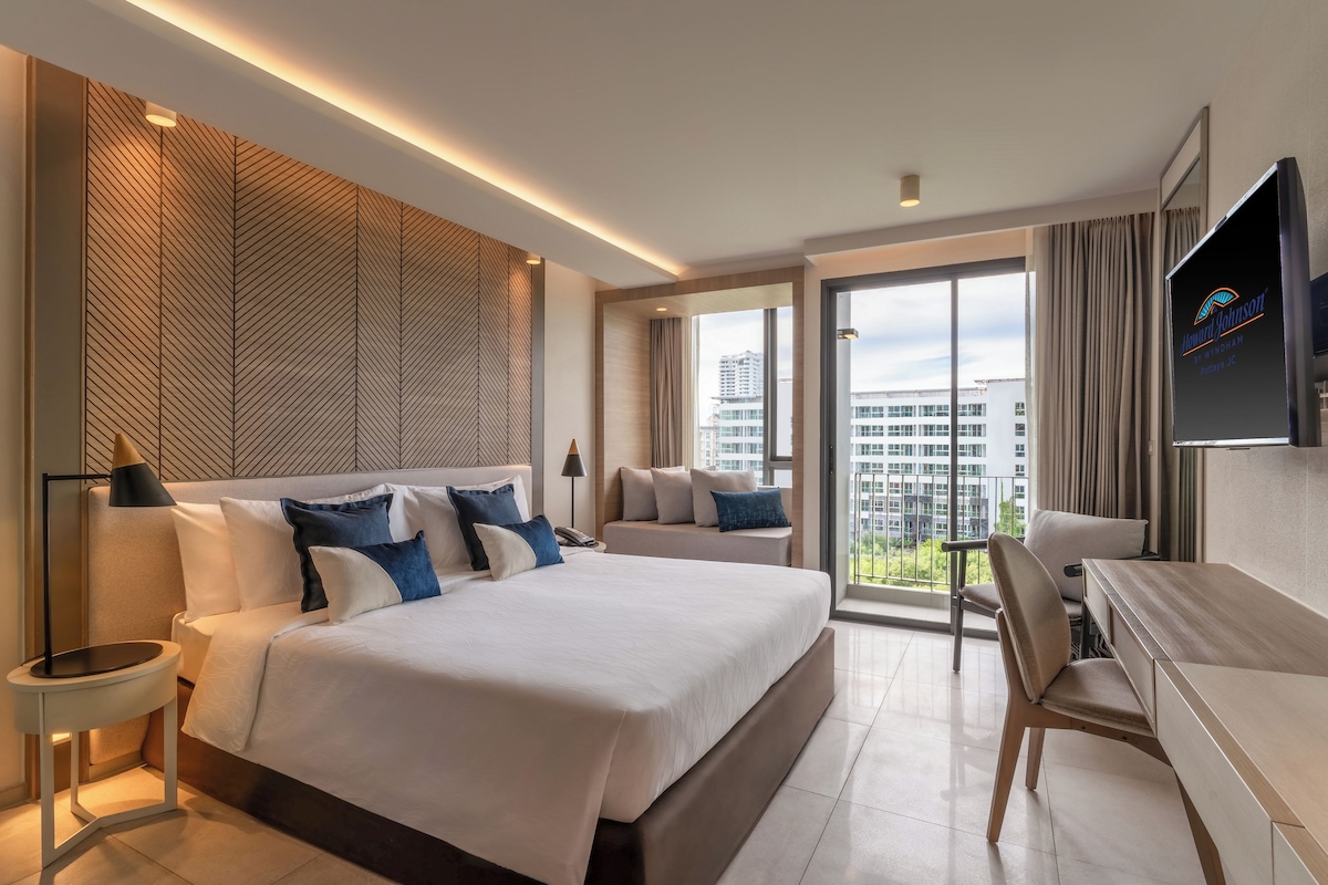 Una habitación de hotel moderna con una cama grande, un escritorio y un televisor.