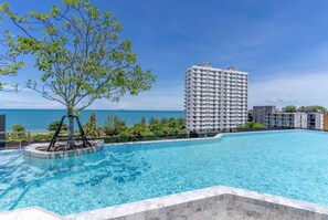 Une piscine avec vue sur la mer et un grand immeuble en arrière-plan.