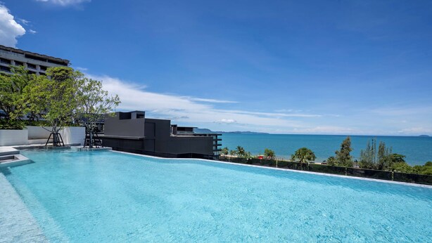 Una piscina con vista al océano y un edificio al fondo.