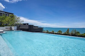 Una piscina con vista al océano y un edificio al fondo.