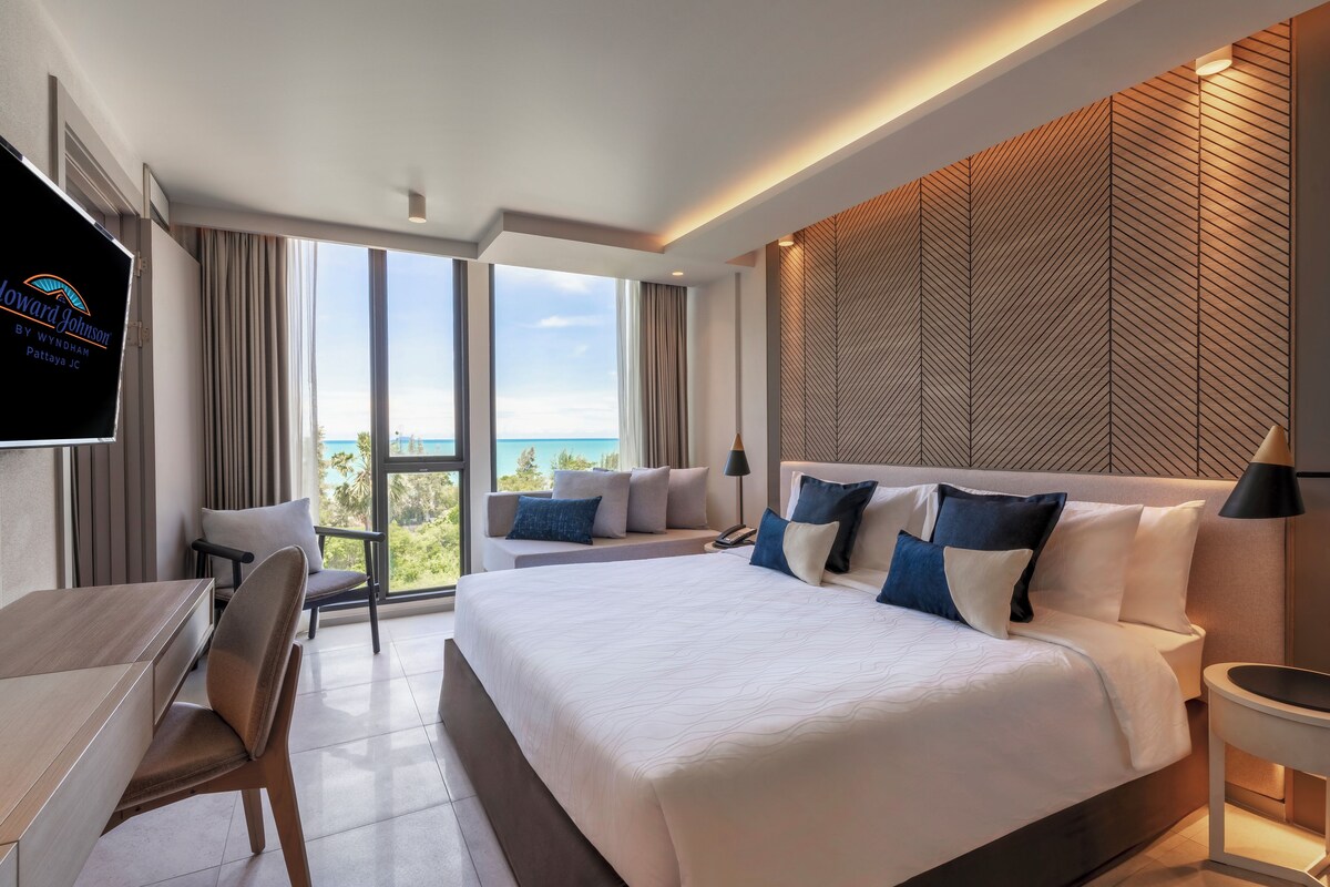 A modern hotel room with a large bed, a desk, and a TV.