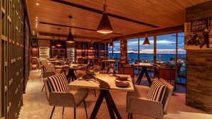 Un comedor moderno con techo de madera y grandes ventanales con vista al mar.