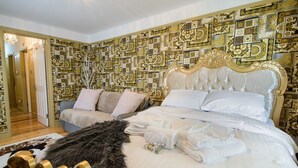 Un dormitorio lujoso con papel tapiz estampado, una cama grande con ropa blanca y un plaid de piel.