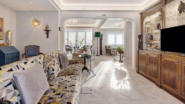 A spacious living room with a patterned sofa, a television, and a decorative cabinet. - Impeccable 4-Bed House in São Domingos de Rana (Sao Domingos de Rana)