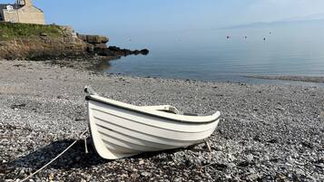 Enjoy a serene coastal retreat with a picturesque beach and a historic stone building in the background.