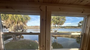 A cabin with two large windows offering views of a lake and trees.