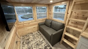 A wooden cabin interior with a sofa, a rug, and a TV.