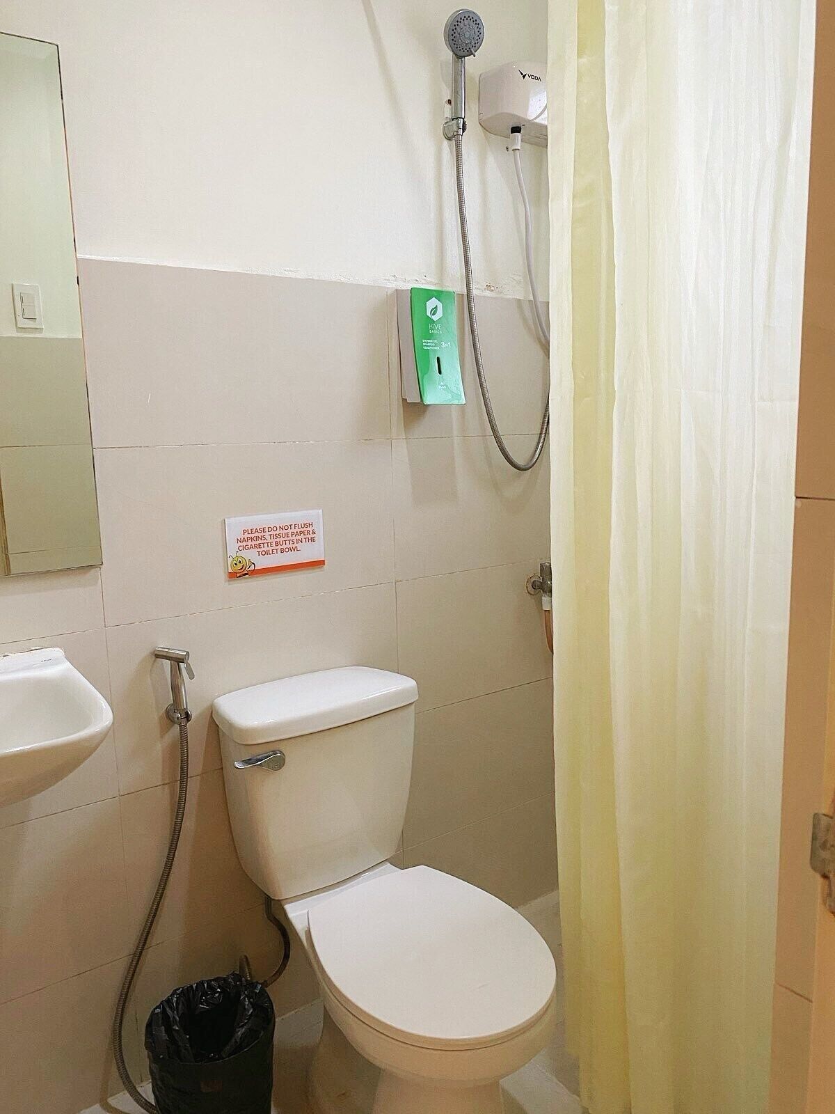 A bathroom with a toilet, a sink, a shower, and a hand dryer.