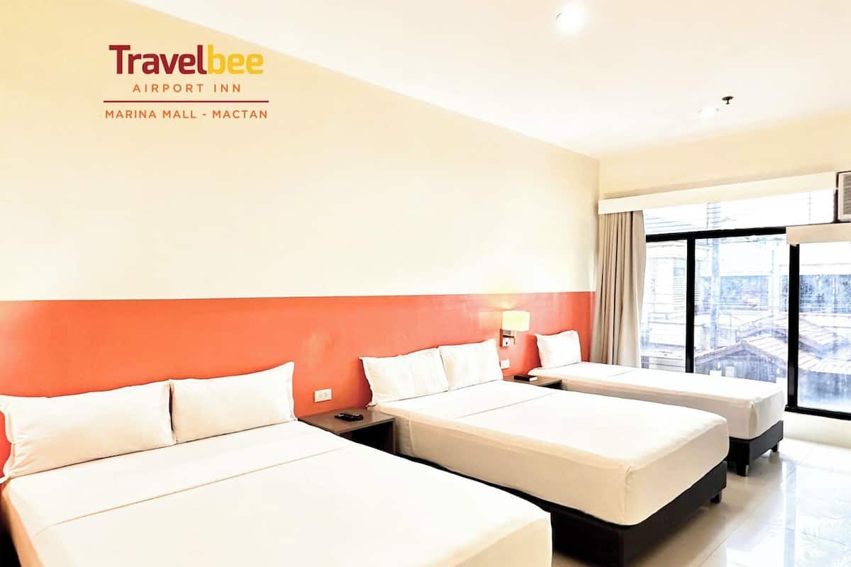 Une chambre de l’hôtel Travelbee Airport Inn, équipée de deux lits, d’une fenêtre avec vue et d’une lampe fixée au mur.