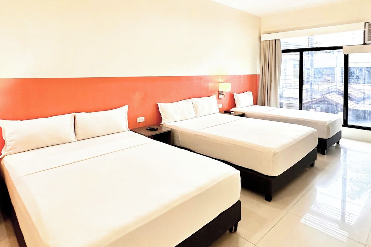 Habitación del Travelbee Airport Inn con dos camas, una ventana con vistas y una lámpara fijada a la pared.