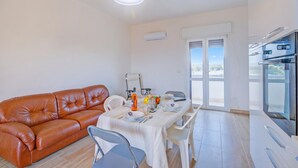 A modern living room with a brown leather sofa, a dining table set with plates, a white tablecloth, and a kitchen area with a refrigerator and oven. - Le Bianche Apt 3 - terrace near the Sea, Manduria, Italy (Manduria)