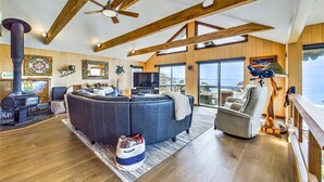 A spacious living room with a large sectional sofa, a fireplace, a television, and a balcony with a view of the sea. - Beachfront home, great for families, ocean access from yard, hot tub (Trinidad)