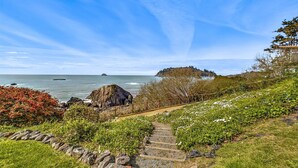 A coastal pathway with steps leading to a grassy area, overlooking the sea and a small island. - Beachfront home, great for families, ocean access from yard, hot tub (Trinidad)