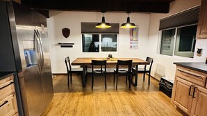 A kitchen with a wooden table, chairs, a refrigerator, and pendant lights. - Big Bear Mountain View Cabin: Jacuzzi, Fire Pit, EV Charger (Big Bear)